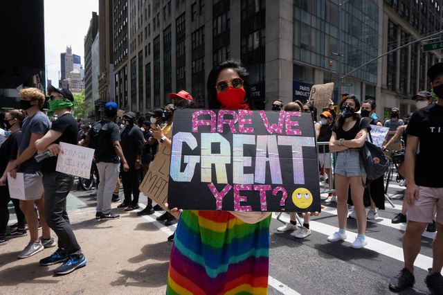 A photo of a Black Lives Matter protester with a sign reading "Are we great yet?"